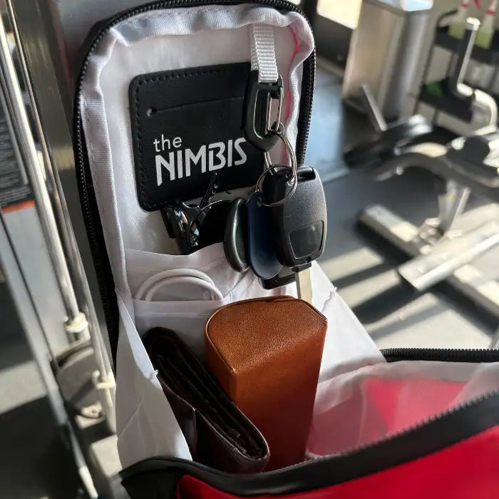 Interior of the Nimbis magnetic gym bag showing organized pockets holding keys, sunglasses, wallet, and accessories in a gym setting.